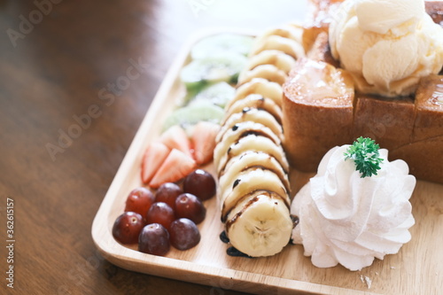 Delectable dessert with honey toast on top by ice cream and various fruits. close up, selective focus photo