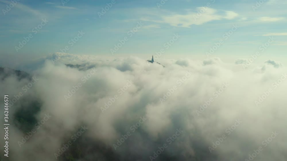 Beautiful fuzzy cloudy in skyscape with antique Buddhism stupa on mountain peak. Aerial view from drone. Flying through the clouds to the old pagoda. Beautiful fuzzy cloudy in skyscape with antique Buddhism stupa on mountain peak. Aerial view from drone. Flying through the clouds to the old pagoda.