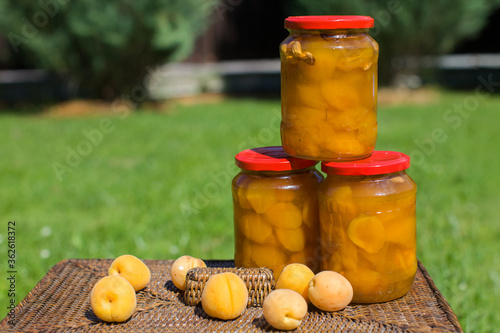 Conservation of apricot jam. Apricot jam jars in a garden on wattled  basket . Conservation of fruit jelly. Canning process.