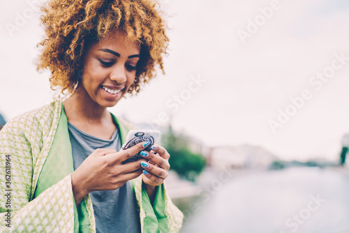 Cropped image of attractive smiling female blogger enjoying leisure time sharing and discussing ideas with followers in personal website.Young happy cute woman recreating outside with modern device