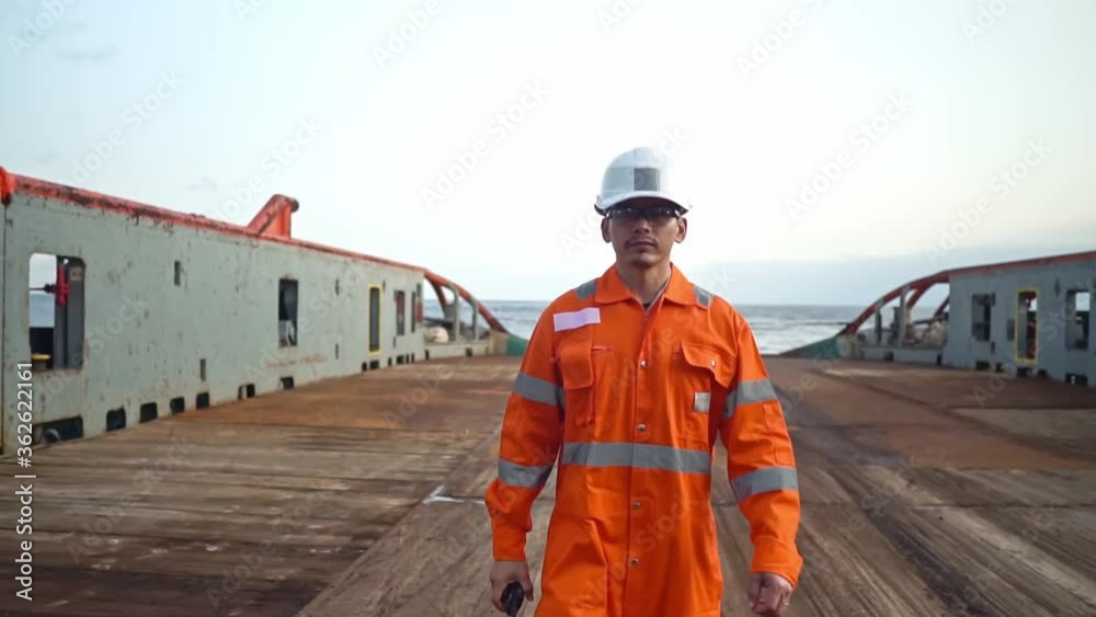 Filipino deck Officer on deck of vessel or ship , wearing PPE personal protective equipment. He speaks to VHF walkie-talkie radio in hands. Dream work at sea Filipino deck Officer on deck of vessel or ship , wearing PPE personal protective equipment. He speaks to VHF walkie-talkie radio in hands. Dream work at sea