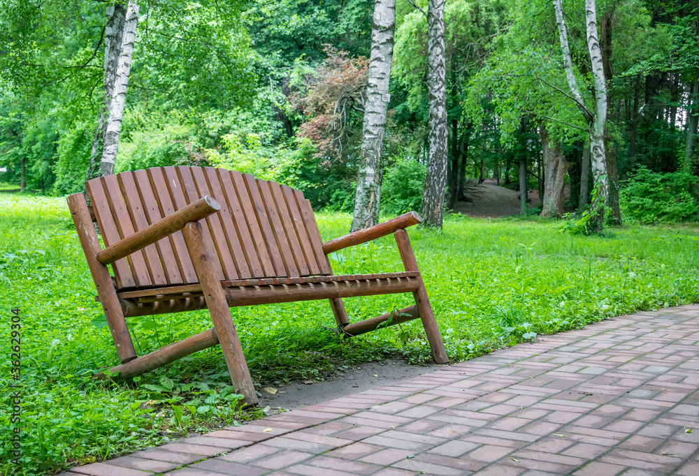 Single isolated wodden bench in the park with green trees in the background. Single isolated wodden bench in the park with green trees in the background.