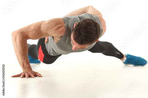 Attractive young man doing push ups exercises from the floor isolated on white background