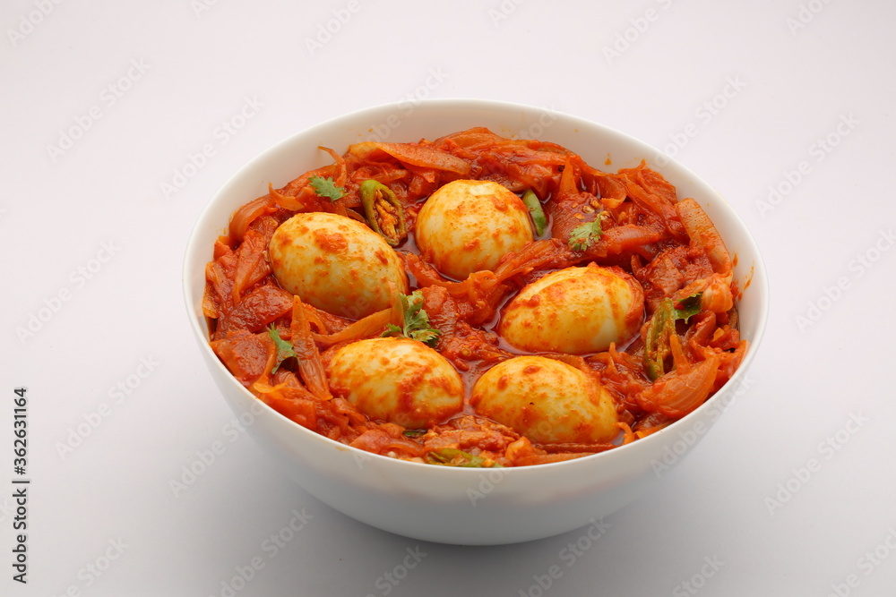 Egg roast or egg masala,spicy reddish dish arranged in a white bowl with white texture Egg roast or egg masala,spicy reddish dish arranged in a white bowl with white texture