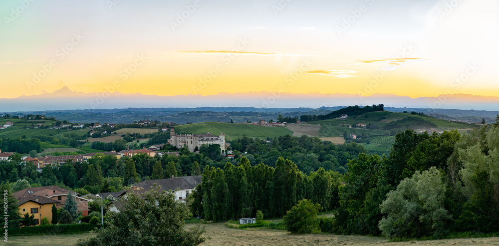 costigliole d'asti town, view of the castle at dust sunset with monviso alps in background. Langhe monferrato wine region, piedmont, Italy