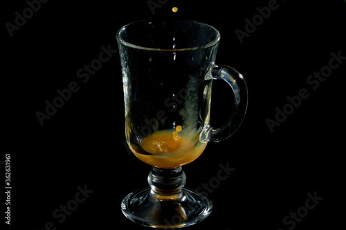 Filling a glass mug with pumpkin juice on black velvet