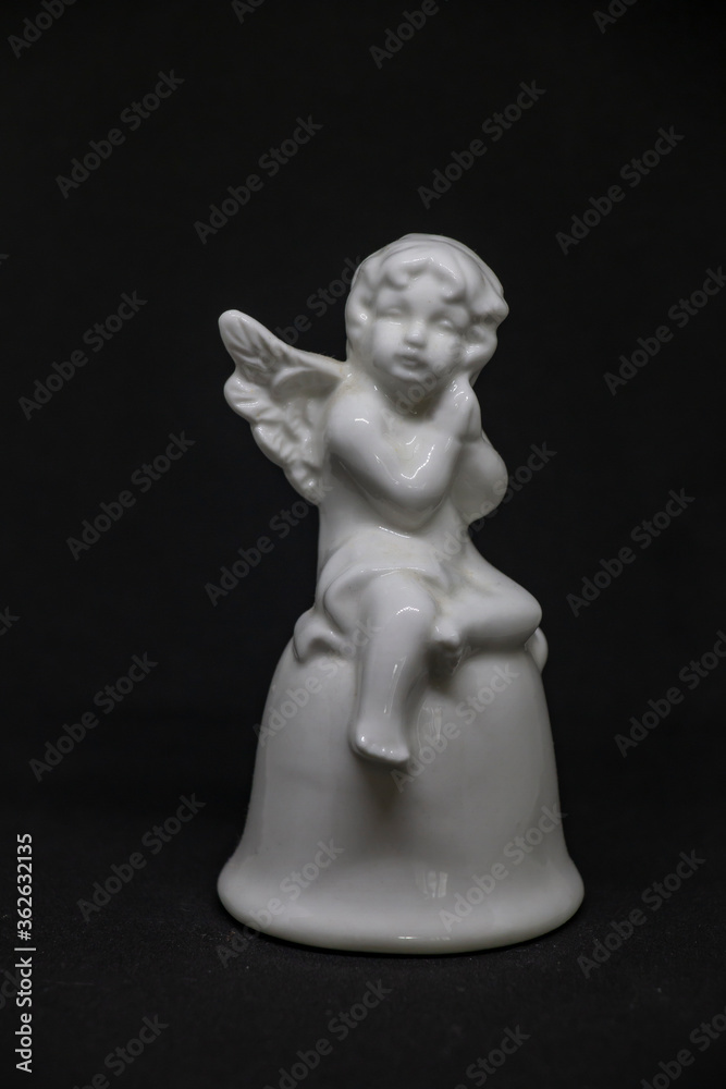 Fototapeta premium white angel doll with a cute face made of clay on a black background