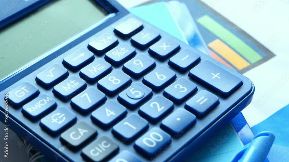 Close up of blue calculator and financial chart on table. Close up of blue calculator and financial chart on table.