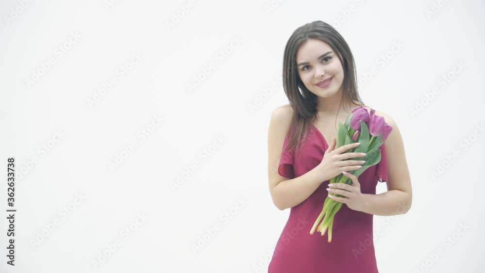 Slowmotion of cute girl with a bouquet of tulips looks with pleasure and smiles tenderly. Slowmotion of cute girl with a bouquet of tulips looks with pleasure and smiles tenderly.