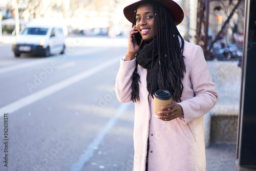 Slika na platnu Cheerful young well-dressed afro american female student standing on urban setti