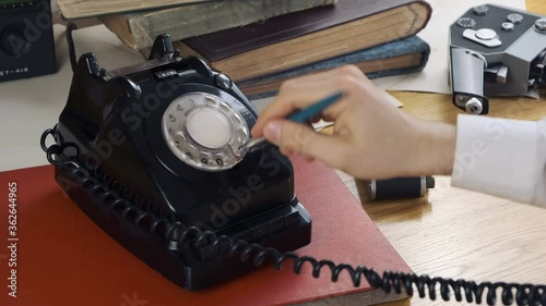 Dialling A Rotary Phone by pen for making call. retro communism concept