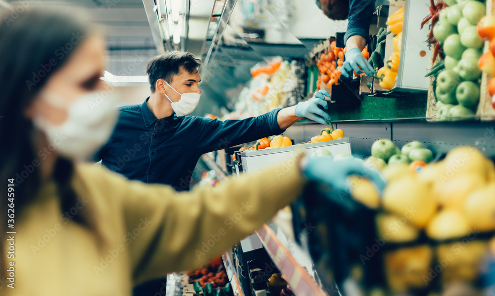 shoppers in protective masks choosing fruit in the supermarket