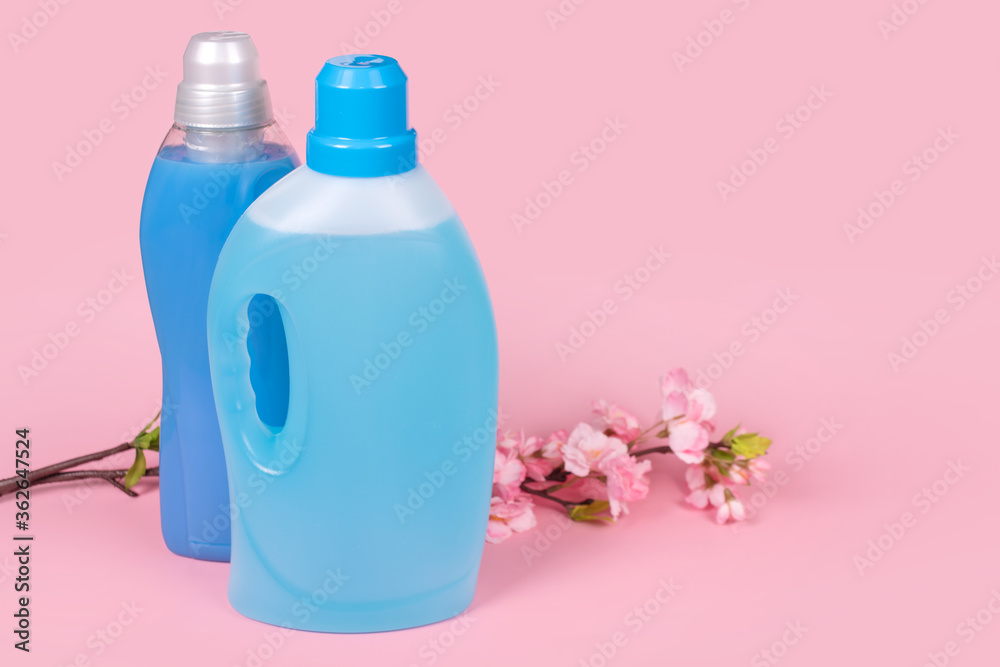 Bottles of detergent and fabric softener on pink background with flowers. Containers of cleaning products, household chemicals. Liquid laundry detergent and conditioner. Laundry day, cleaning concept. Bottles of detergent and fabric softener on pink background with flowers. Containers of cleaning products, household chemicals. Liquid laundry detergent and conditioner. Laundry day, cleaning concept.