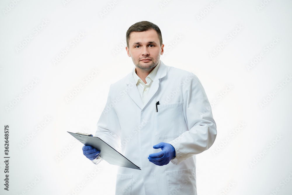 A serious male caucasian doctor in a white lab coat and blue disposable medical gloves is holding a cardboard with a patient card with a diagnosis. A scientist is isolated over white background. A serious male caucasian doctor in a white lab coat and blue disposable medical gloves is holding a cardboard with a patient card with a diagnosis. A scientist is isolated over white background.