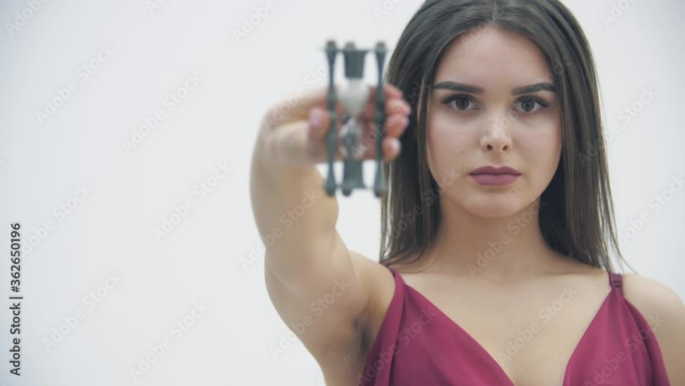 Young female turns hourglass and watches time passing together with the sand. Young female turns hourglass and watches time passing together with the sand.