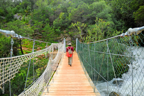Woman with backpack crossing a wooden footbridge in the Guadiaro river near the Canyon of the Buitreras famous gorge located in the Alcornocales Natural Park Malaga province Andalusia Spain photo