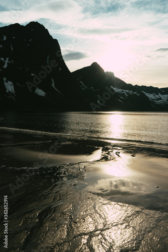 Beautiful sunset on the norwegian beach. Stream flowing into the sea. Amazing mountains in the background. Fjord on the northern Norway, Senja island.