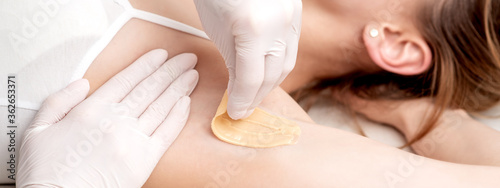 Hand of cosmetologist applying wax paste on armpit. Depilation or epilation female armpit with liquid sugar paste. Smooth underarm concept