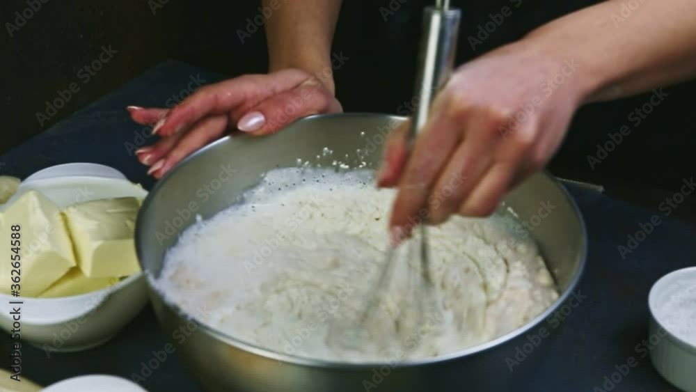 slow motion closeup female hands by whisk mixing liquid dough with white flour slow motion closeup female hands by whisk mixing liquid dough with white flour