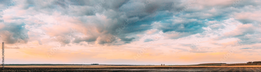 Fototapeta premium Sunset Sky Above Empty Spring Countryside Rural Soil Landscape. Field Under Sunny Spring Sky. Agricultural Landscape With Copy Space. Panorama