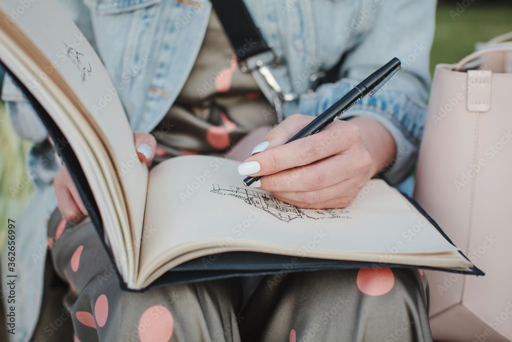 Sketchbook with a drawing of a house close-up. Girl draws in the fresh air. Front view Sketchbook with a drawing of a house close-up. Girl draws in the fresh air. Front view