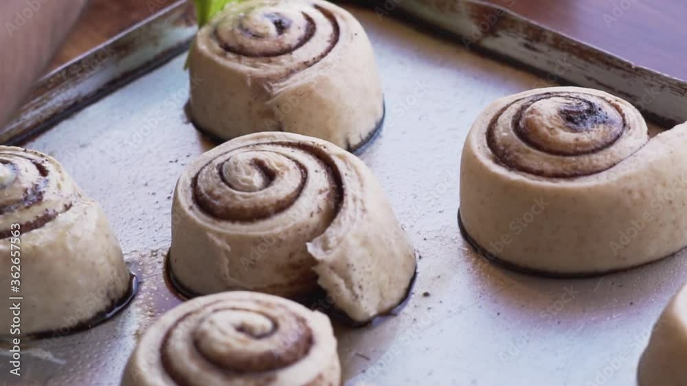 Man's Hand Brushing The Cinnamon Rolls With Sweet Mixture. - slow motion Man's Hand Brushing The Cinnamon Rolls With Sweet Mixture. - slow motion