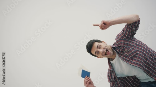 4k slowmotion of man holding tickets for plane and passport ready for travelling, dancing and inviting you to go with him. photo