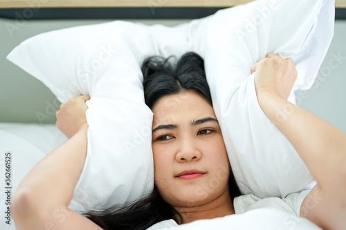 young attrative Asian woman on white pillow and bed sheet in bedroom relaxing on holiday stay home photo