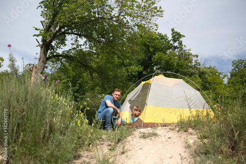 Happy family dad and child on camping trip relaxing inside tent. Staycations, hyper-local travel, family outing, getaway.