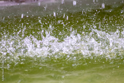 Raindrops falling to the floor in heavy rain day into a puddle on an splashy country road in spring offer a refreshing water shower for plants and trees after an absolute drought and meagerness