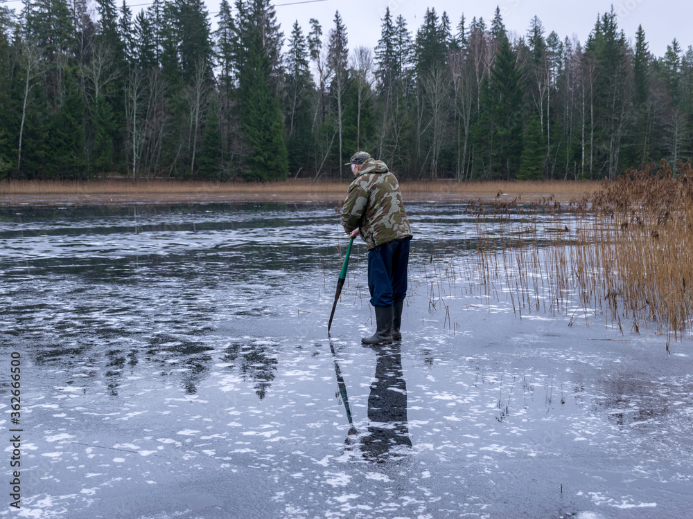 winter angler checks the strength and thickness of the ice winter angler checks the strength and thickness of the ice