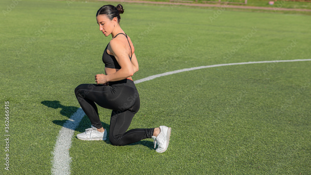 fitness, sports, exercises, training and the concept of people-a girl does an exercise on the triceps, legs and abs on the city sports field. The concept of a healthy lifestyle