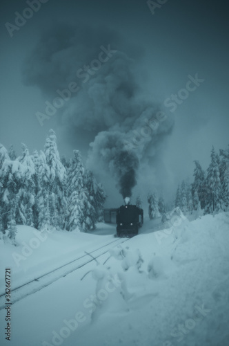 Historic steam train in the winter mountain landscape with snow nature driving to the top of the Brocken. Harzer Schmalspurbahn. Harz Mountains, Harz National Park in Germany.