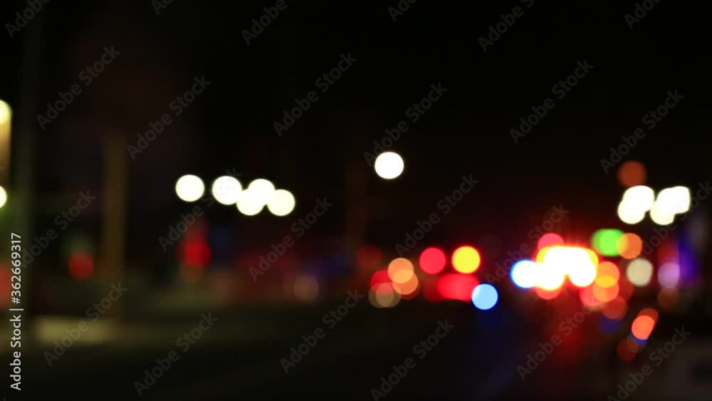 Out of focus bokeh police and fire lights on a city street at night.
