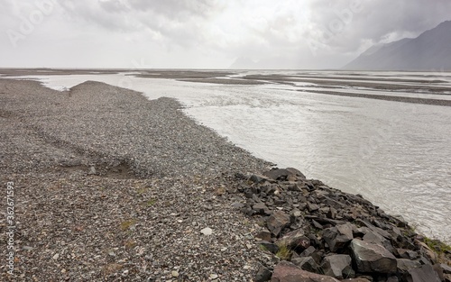 Gravel and stone shore near the river and ocean in Stafafell area in Iceland photo