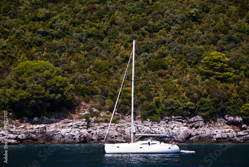 A yacht sailing in the Bay along the rocky shore