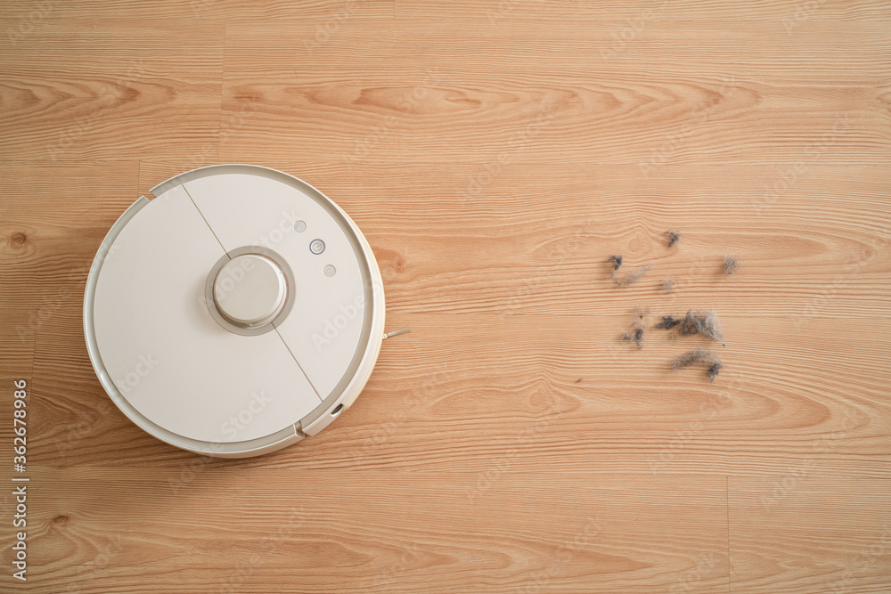 robot vacuum cleaner removes dust in room on brown floor. vacuum cleaner in ordinary apartment. modern household wireless device for cleaning house. smart home concept robot vacuum cleaner removes dust in room on brown floor. vacuum cleaner in ordinary apartment. modern household wireless device for cleaning house. smart home concept