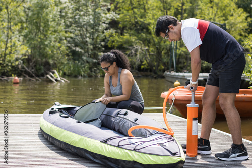 A COUPLE OF MAN AND WOMAN INFLATING A KAYAK