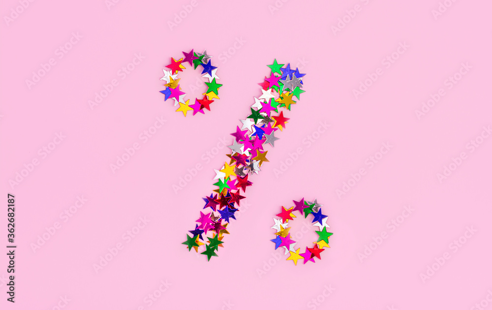 Discount symbol from multi color stars on a pink background. A Percentage Sign, christmas sales