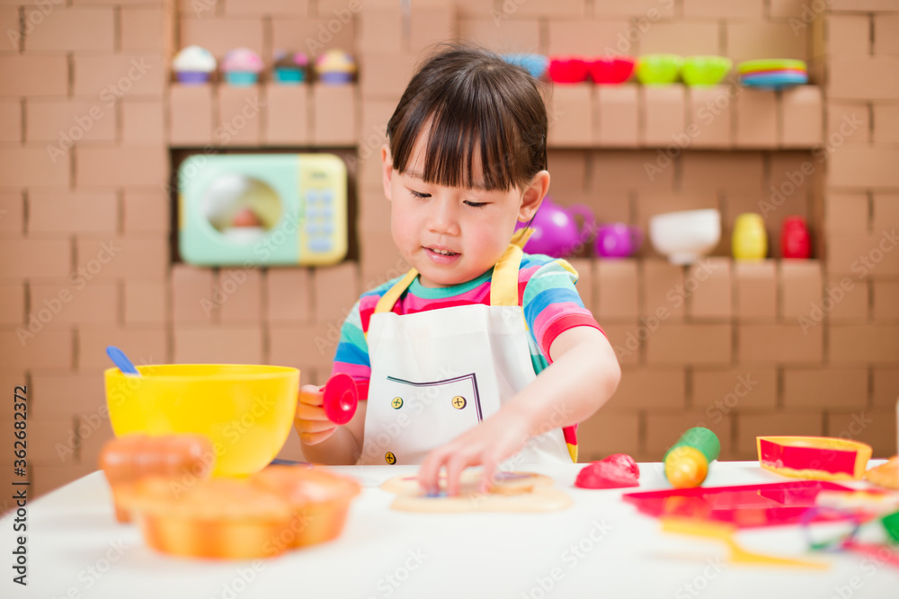 toddler girl pretend play food preparing role against cardboard blocks kitchen background toddler girl pretend play food preparing role against cardboard blocks kitchen background