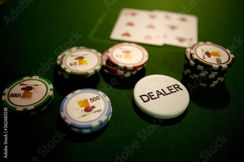 Fotografie Chips and playing cards at a casino card game with dealer chip on green baize
