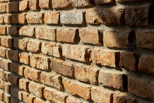 Closeup of old grunge brick wall in natural light. Rough surface  loft style  orange colour. Side view  shallow depth of field  texture or background.
