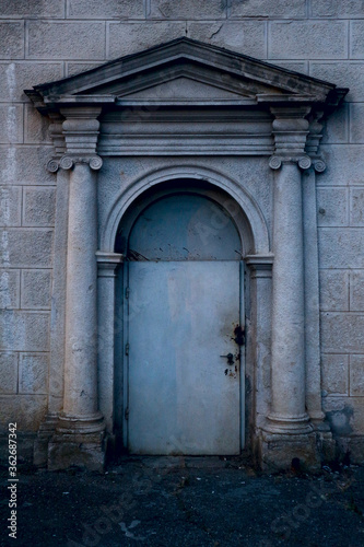 Old gloomy closed door with porch. © Mila Che