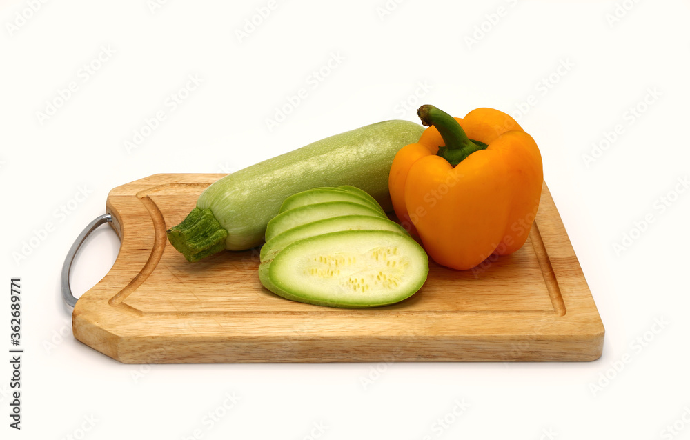 Zucchini and ripe sweet pepper of different colors on a cutting board on a light background. Natural product. Natural color. Close-up. Zucchini and ripe sweet pepper of different colors on a cutting board on a light background. Natural product. Natural color. Close-up.