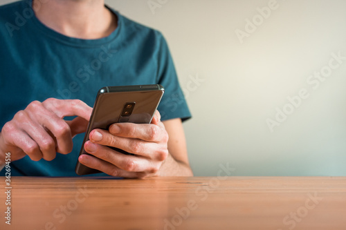 young man using his smartphone and texting inside his house