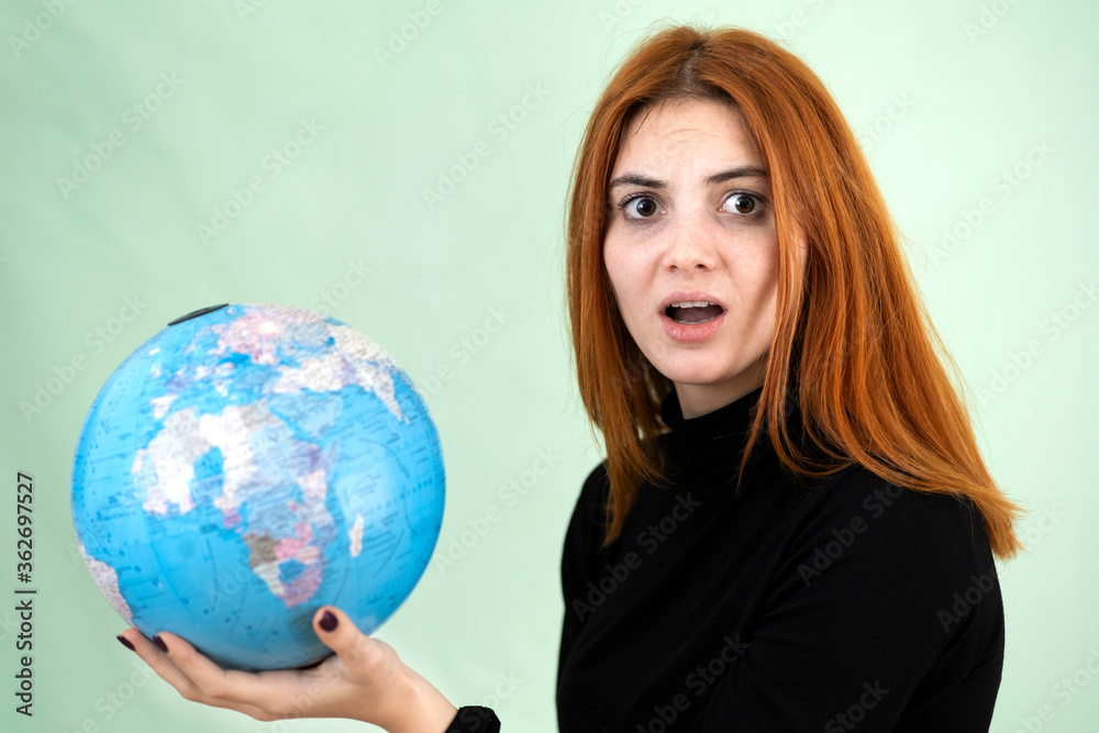 Portrait of a sad worried young woman holding geographic globe of the world in her hands. Travel destination and planet protection concept. Portrait of a sad worried young woman holding geographic globe of the world in her hands. Travel destination and planet protection concept.