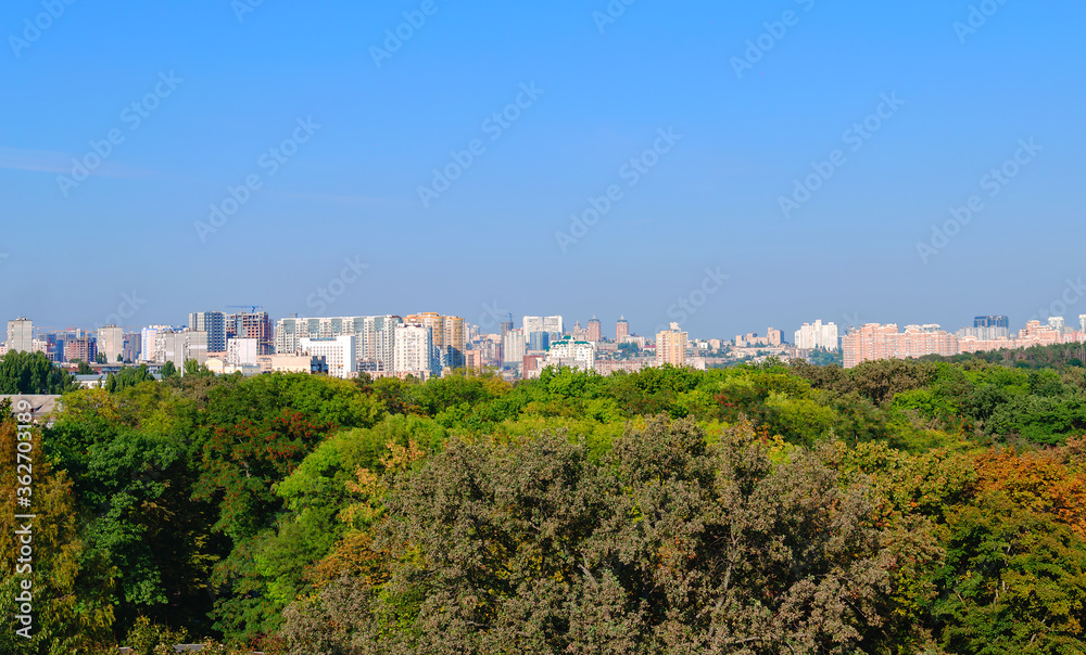 beautiful autumn landscape from a height, bright trees on a background of the city