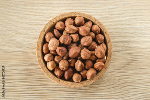 Hazelnuts in the bowl on wooden background, concept of healthy eating vegan food. Top view, selective focus, copy space