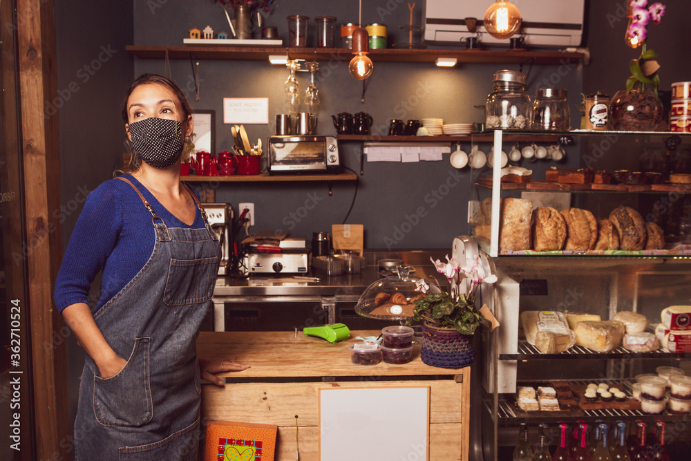 Caucasian woman posing waiting for customer in a small business wearing mask durind covid-19 pandemic reopening after quarantine Caucasian woman posing waiting for customer in a small business wearing mask durind covid-19 pandemic reopening after quarantine