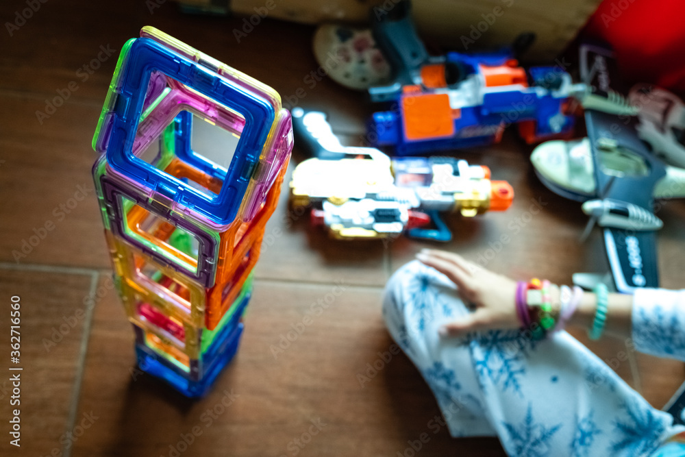 Fototapeta premium Little girl completing a tower with magnetic pieces inside her room.